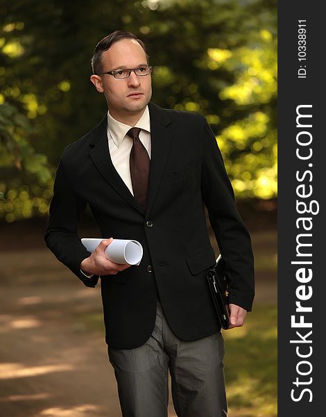Businessman holding bag and blueprint outdoors. Businessman holding bag and blueprint outdoors