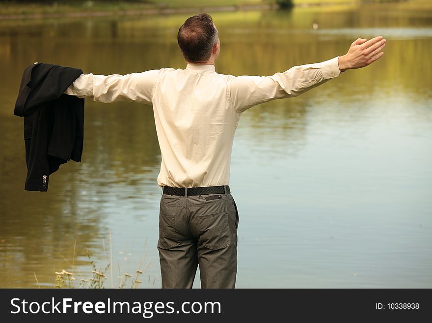 Businessman standing with spread arms at the lake. Businessman standing with spread arms at the lake