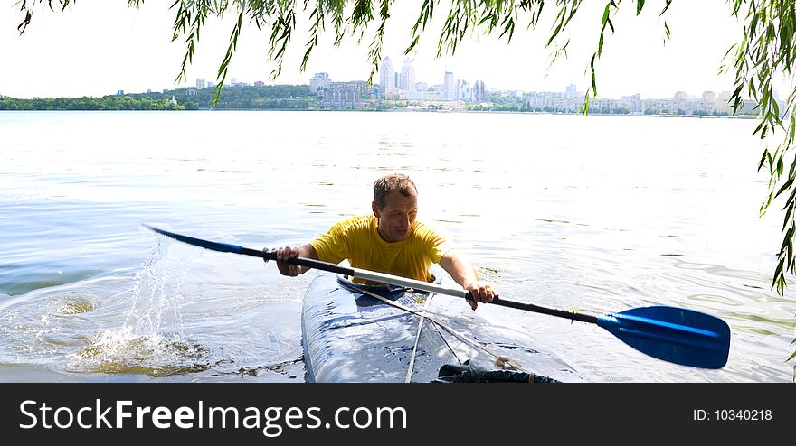 A man in a kayak swims at shore of the river