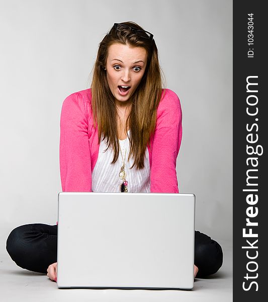 Attractive young woman shocked and frustrated with her laptop against neutral background. Attractive young woman shocked and frustrated with her laptop against neutral background