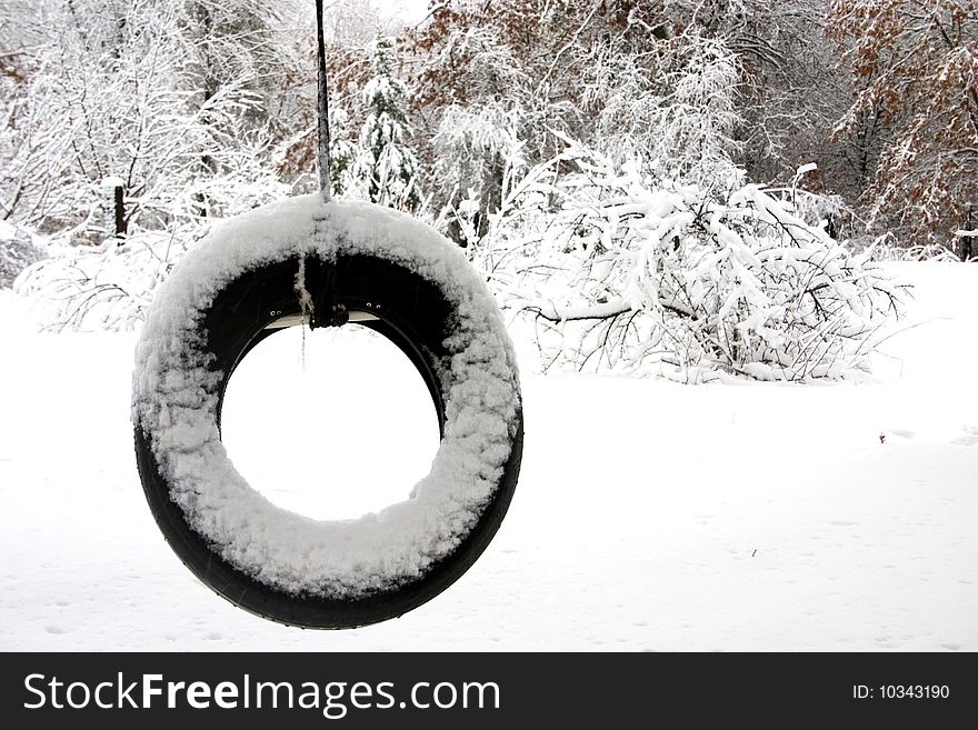 A snow covered tire swing. A snow covered tire swing