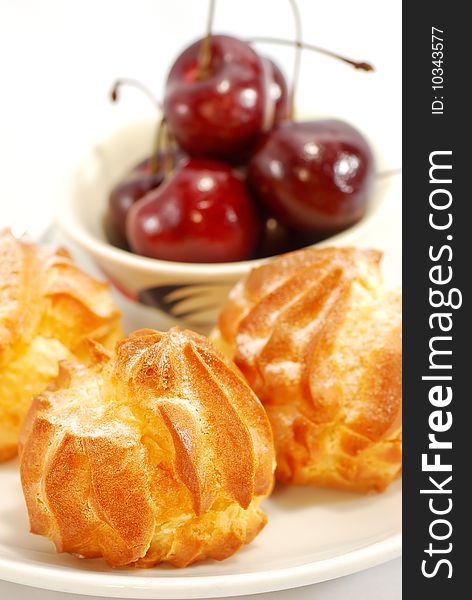 Cream puff and fresh cherry on plate with white background. Cream puff and fresh cherry on plate with white background