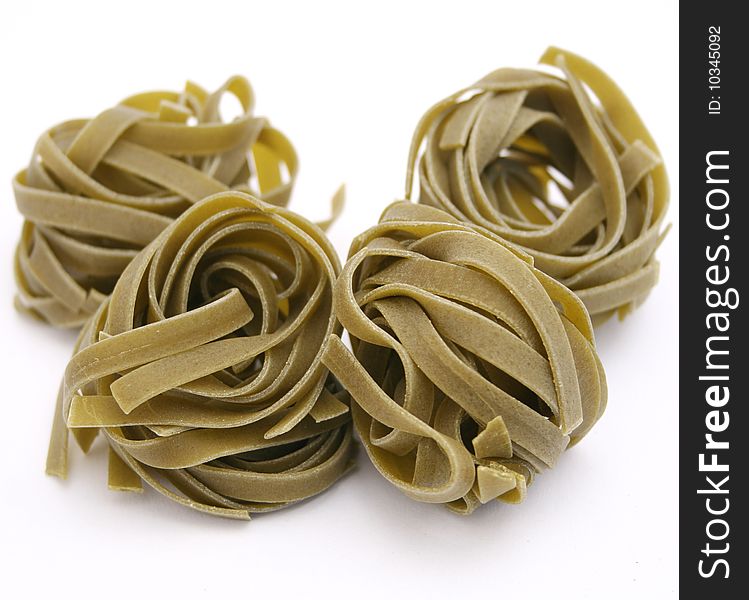 Some uncooked italian pasta with spinach on white background