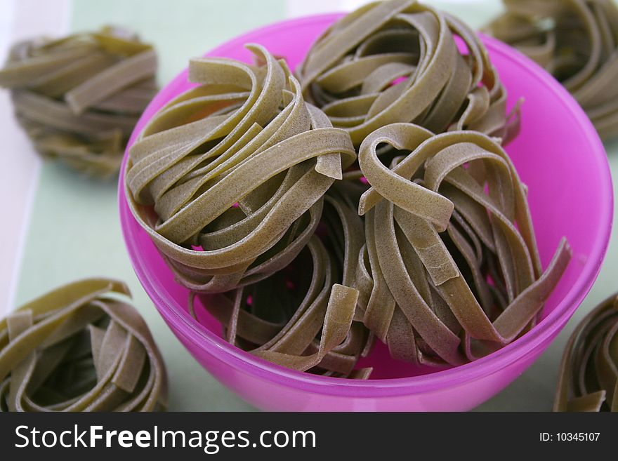 Some uncooked italian pasta with spinach in a bowl