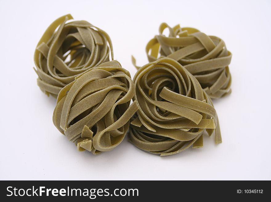 Some uncooked italian pasta with spinach on white background