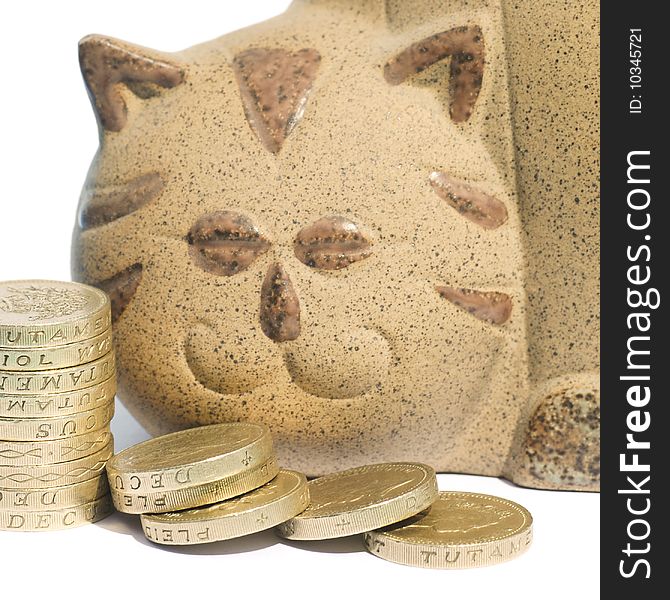 Pile of coins in front of cat shaped piggy bank. Pile of coins in front of cat shaped piggy bank