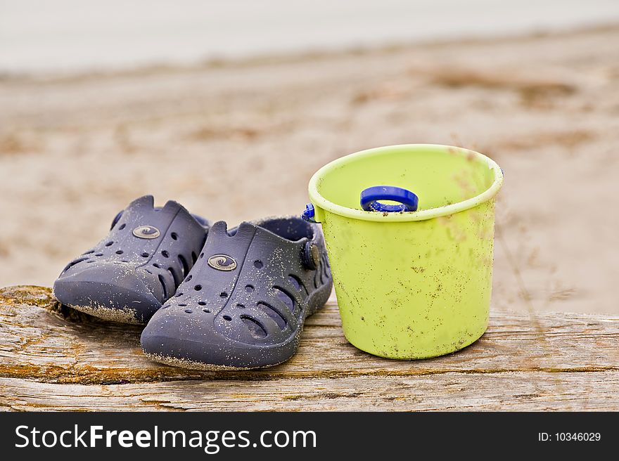 A pair of sandals with a pail on the beach. A pair of sandals with a pail on the beach