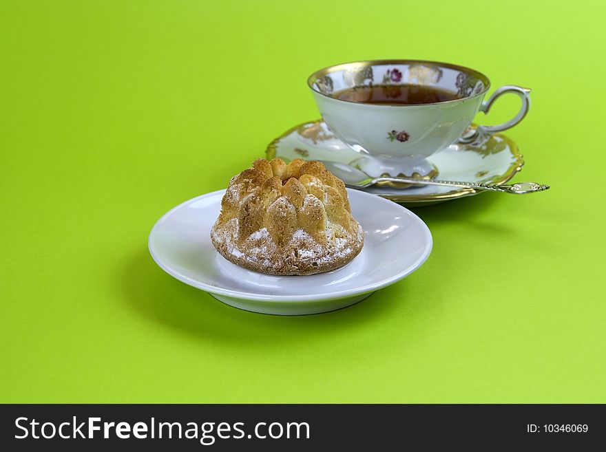 Cake and tea on the saucer and the green background. Cake and tea on the saucer and the green background