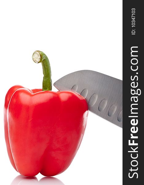 A vertical image of a red pepper being sliced on white