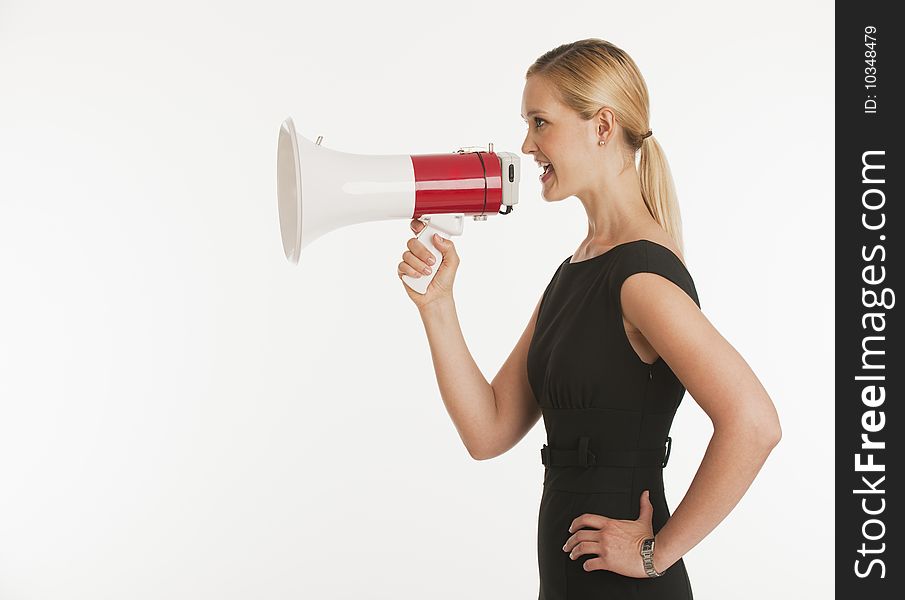 Businesswoman yelling into megaphone with white seamless background