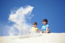 Two Boys Sit On Sand And Scatter It Royalty Free Stock Images