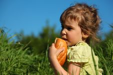Girl Eats Bread In Grass Against Blue Sky Royalty Free Stock Photos