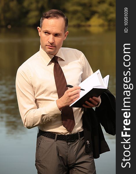 Businessman making notes standing at the shore