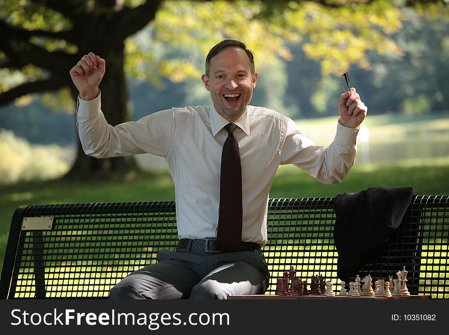 Happy businessman playing chess in a city park