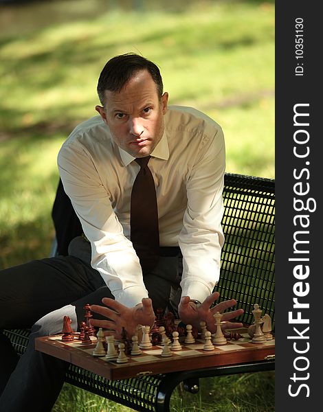 Angry businessman playing chess in a city park. Angry businessman playing chess in a city park
