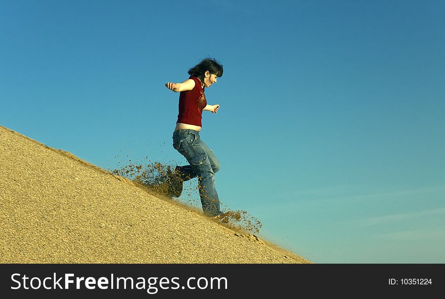 Woman barefoot running down a sand dune