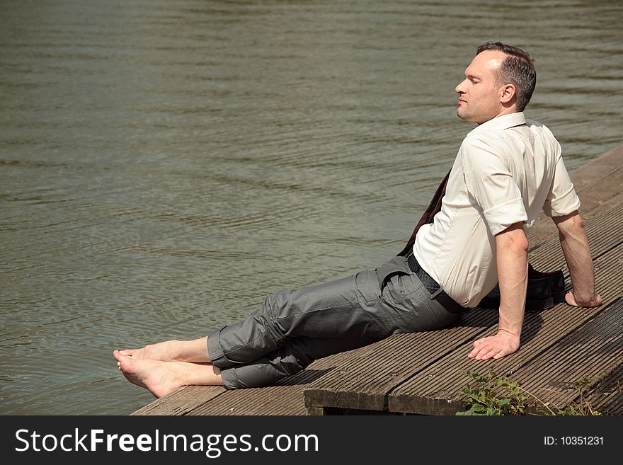 Businessman relaxing on the wooden pier after work. Businessman relaxing on the wooden pier after work