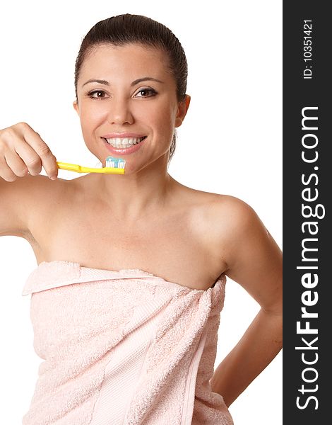 Smiling woman holding a toothbrush with toothpaste about to brush her teeth.