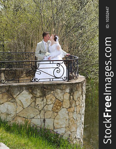 Happy groom and the bride kiss in park. Happy groom and the bride kiss in park.