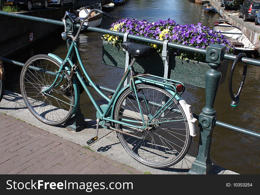 Bike locked to a bridge over a canal in Amsterdam. Bike locked to a bridge over a canal in Amsterdam