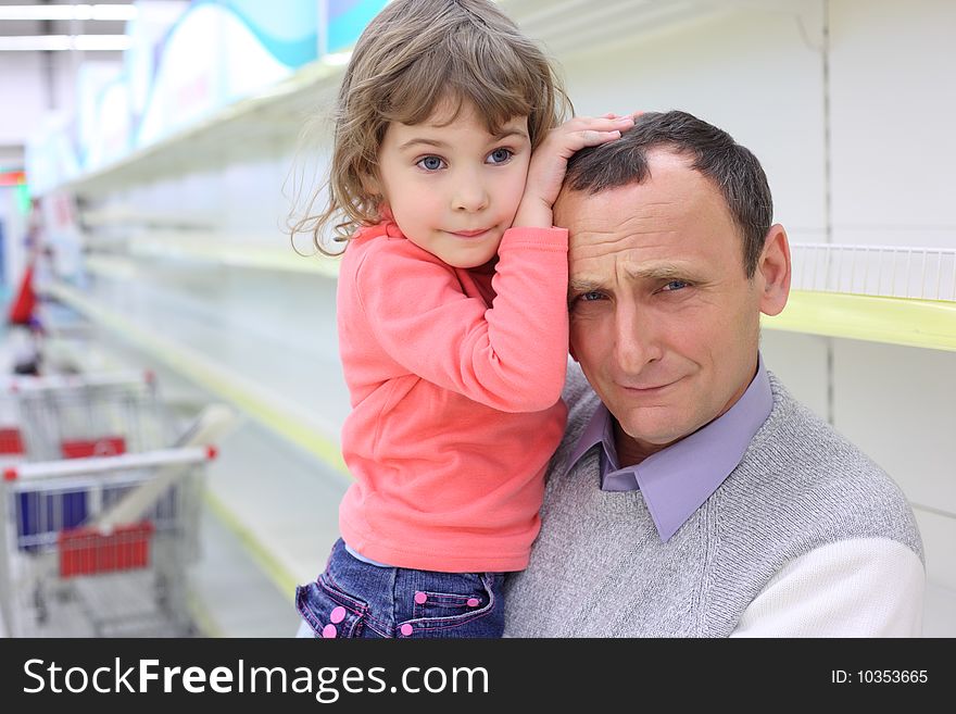 Elderly man at empty shelves in  shop with child on hands. Elderly man at empty shelves in  shop with child on hands