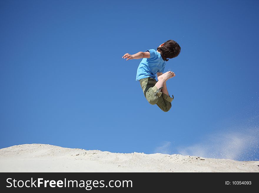 Boy jumps on sand, summer day