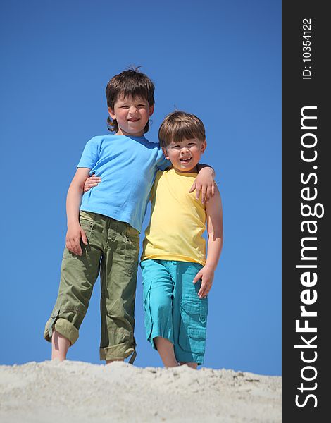 Two boys embrace each other on sand