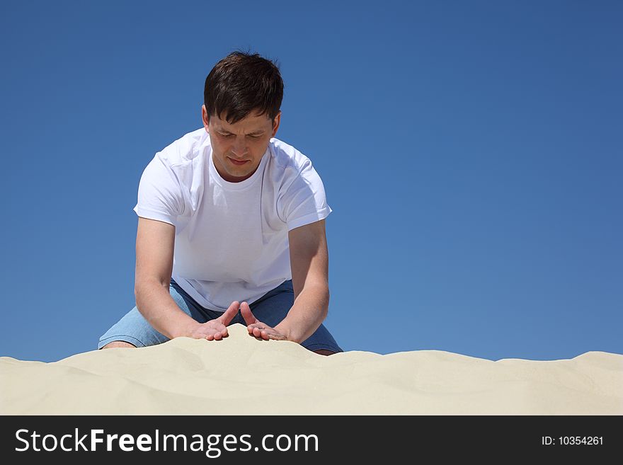 Guy plays in sand against blue sky, summer day. Guy plays in sand against blue sky, summer day