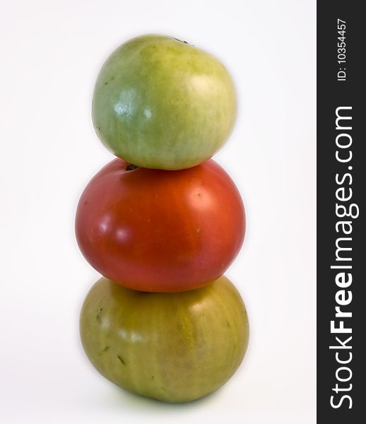 Three tomatoes, two green and one red, piled to form a totem. Three tomatoes, two green and one red, piled to form a totem.