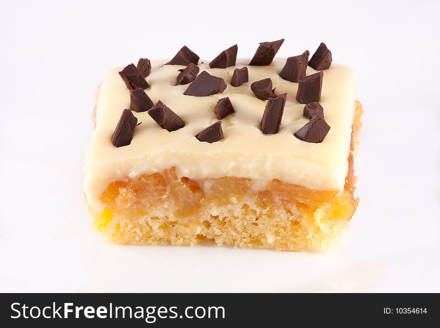 Slice of peach cake with pieces of chocolate and vanilla cream topping. Slice of peach cake with pieces of chocolate and vanilla cream topping