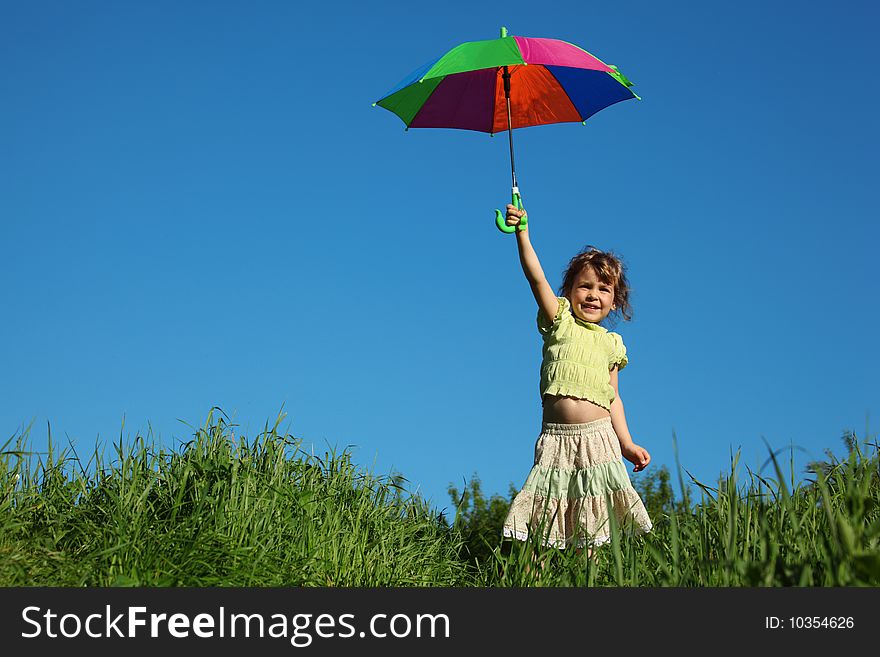 Girl with multicoloured umbrella in lifted hand in grass. Girl with multicoloured umbrella in lifted hand in grass