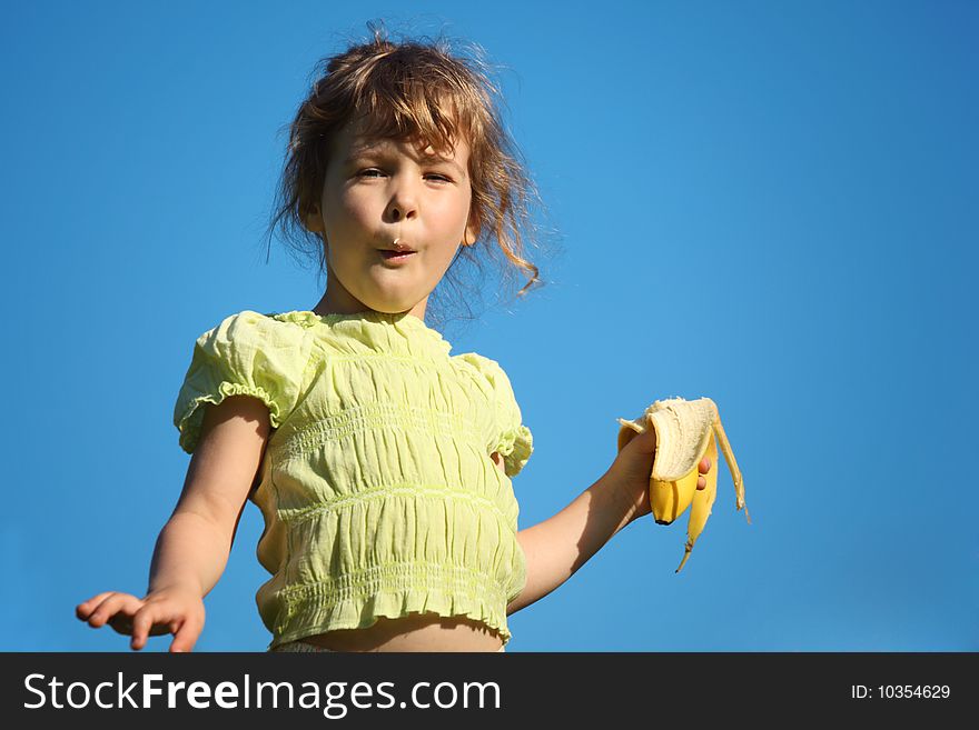Girl eats banana against blue sky