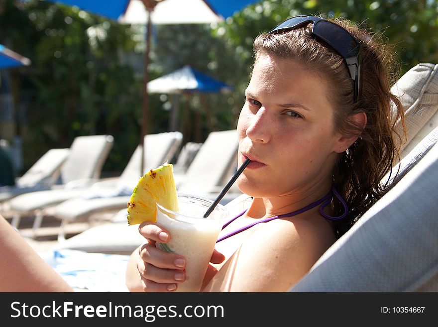 Young woman is chilling on a pool bed with a cocktail in her hand. Young woman is chilling on a pool bed with a cocktail in her hand.