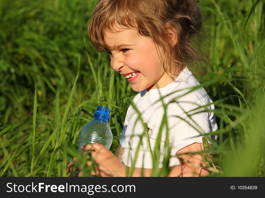 Smiling Girl In Grass With Plastic Bottle