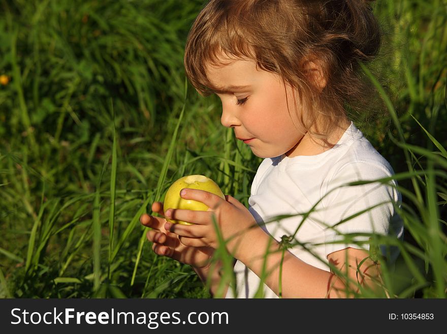 Little girl in grass with green apple