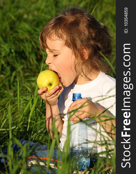 Girl With Plastic Bottle Eats Green Apple