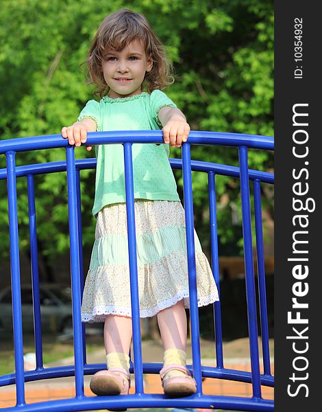 Little girl stands on bridge on playground