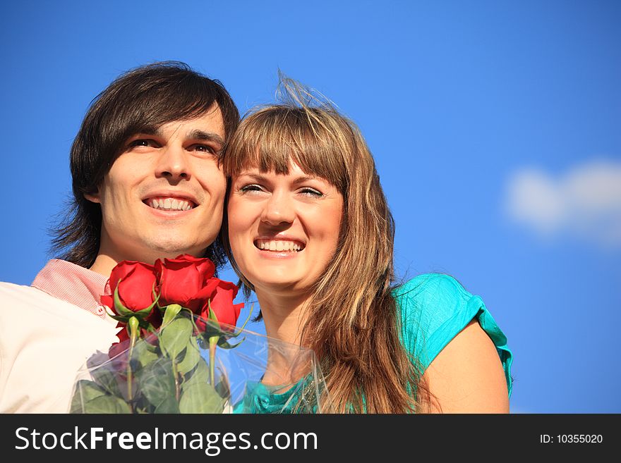 Young pair with bouquet of roses against sky