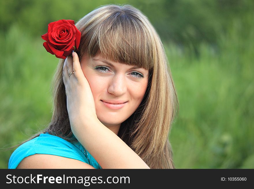 Smiling girl with red rose in hair