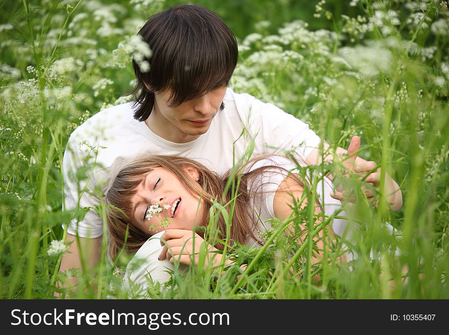 Girl lies in lap of guy sitting in green grass