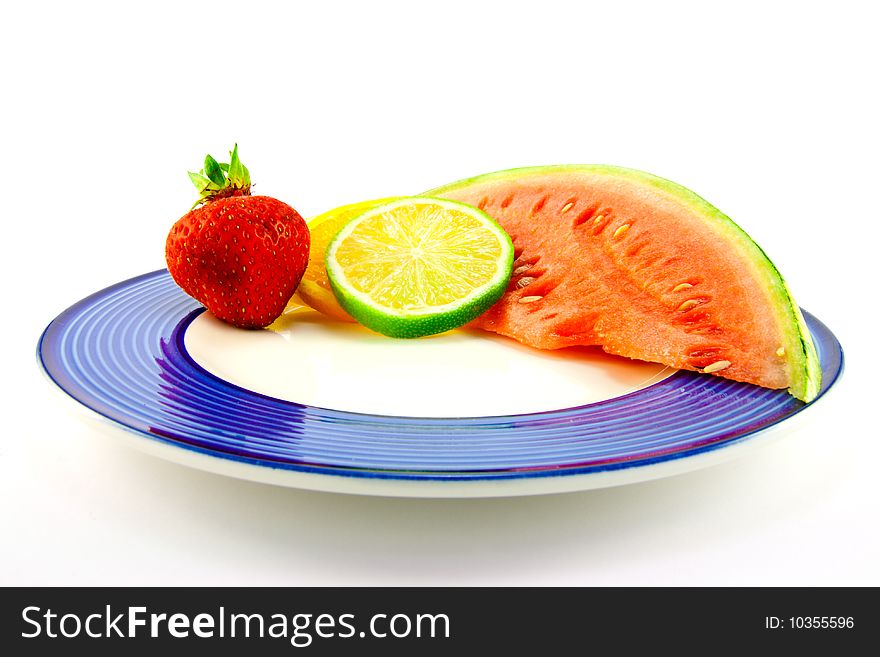 Slice of red juicy watermelon with lemon, lime and orange slices and single strawberry on a blue plate with a white background. Slice of red juicy watermelon with lemon, lime and orange slices and single strawberry on a blue plate with a white background