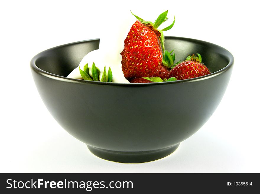 Whole red ripe strawberries with cream in a black bowl on a white background. Whole red ripe strawberries with cream in a black bowl on a white background