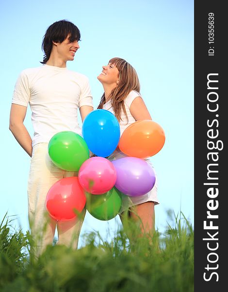 Girl and guy stand in grass with multicoloured balloons. Girl and guy stand in grass with multicoloured balloons