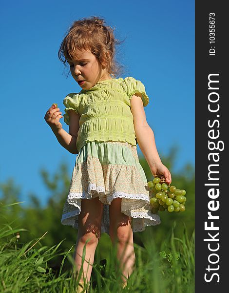 Girl eats grape against blue sky