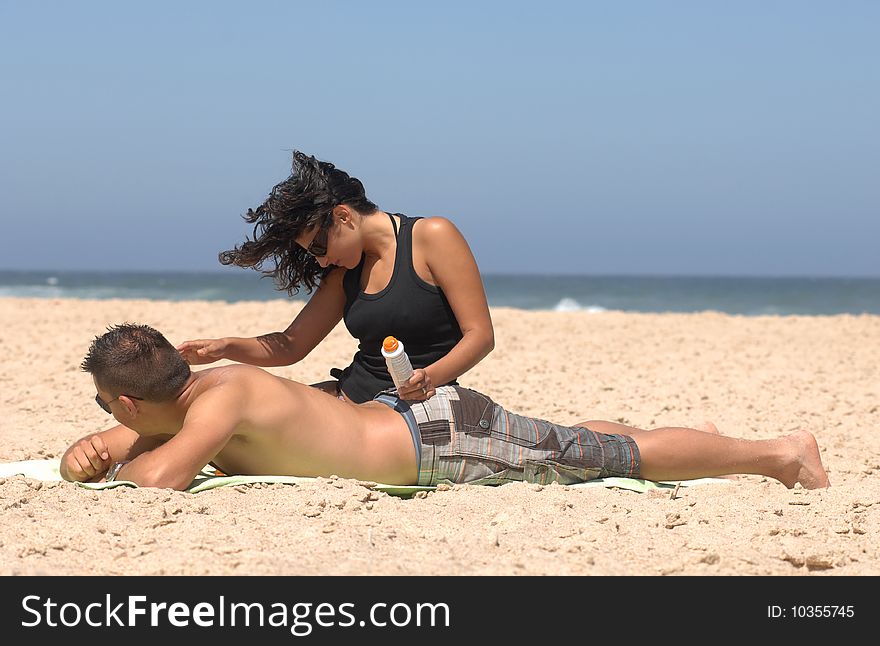 Lovely romantic couple applying suncream on the beach