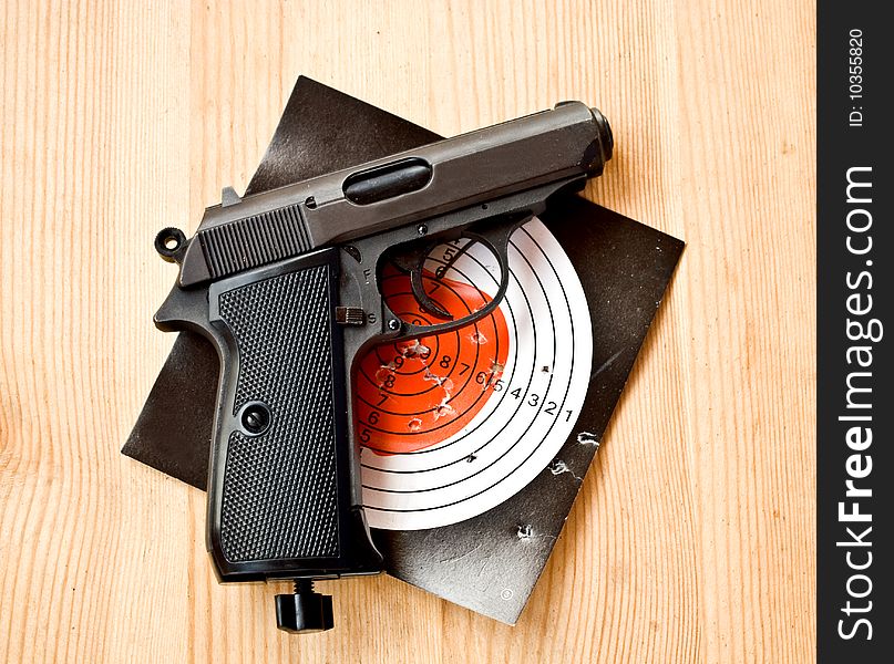 Gun with dartboard with hole from shot