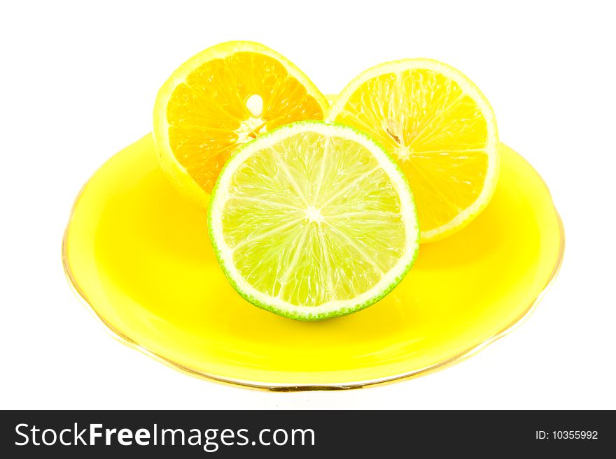 Lemon, lime and orange half on a fancy yellow plate on a white background. Lemon, lime and orange half on a fancy yellow plate on a white background