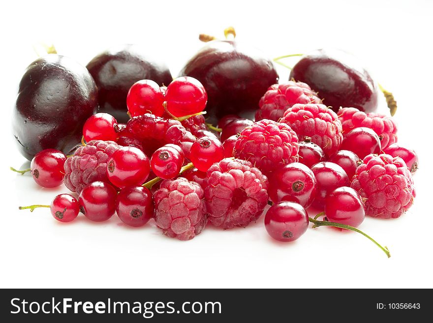 Pile of raspberries, currants and cherries isolated over white background macro shot