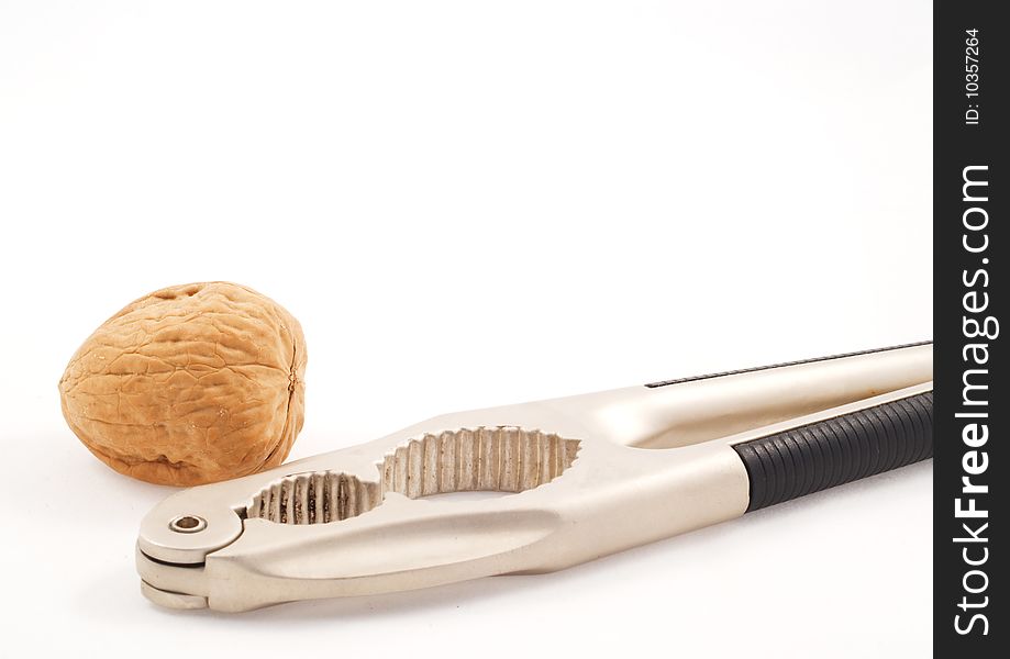 Walnut with a metal nutcracker over a white background. Walnut with a metal nutcracker over a white background.