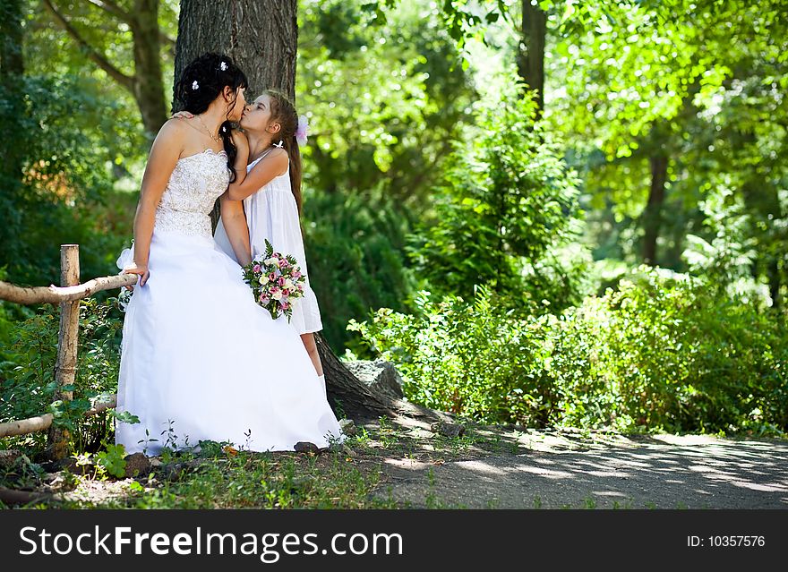 The bride in a white dress kisses the daughter. The bride in a white dress kisses the daughter